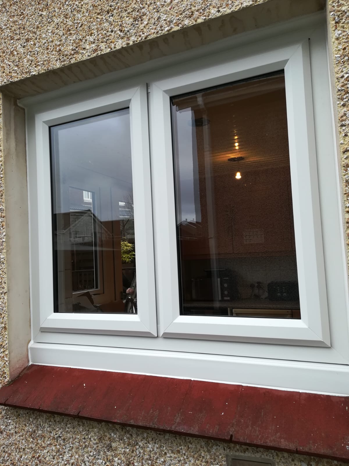 White uPVC double casement window on render wall, exterior view