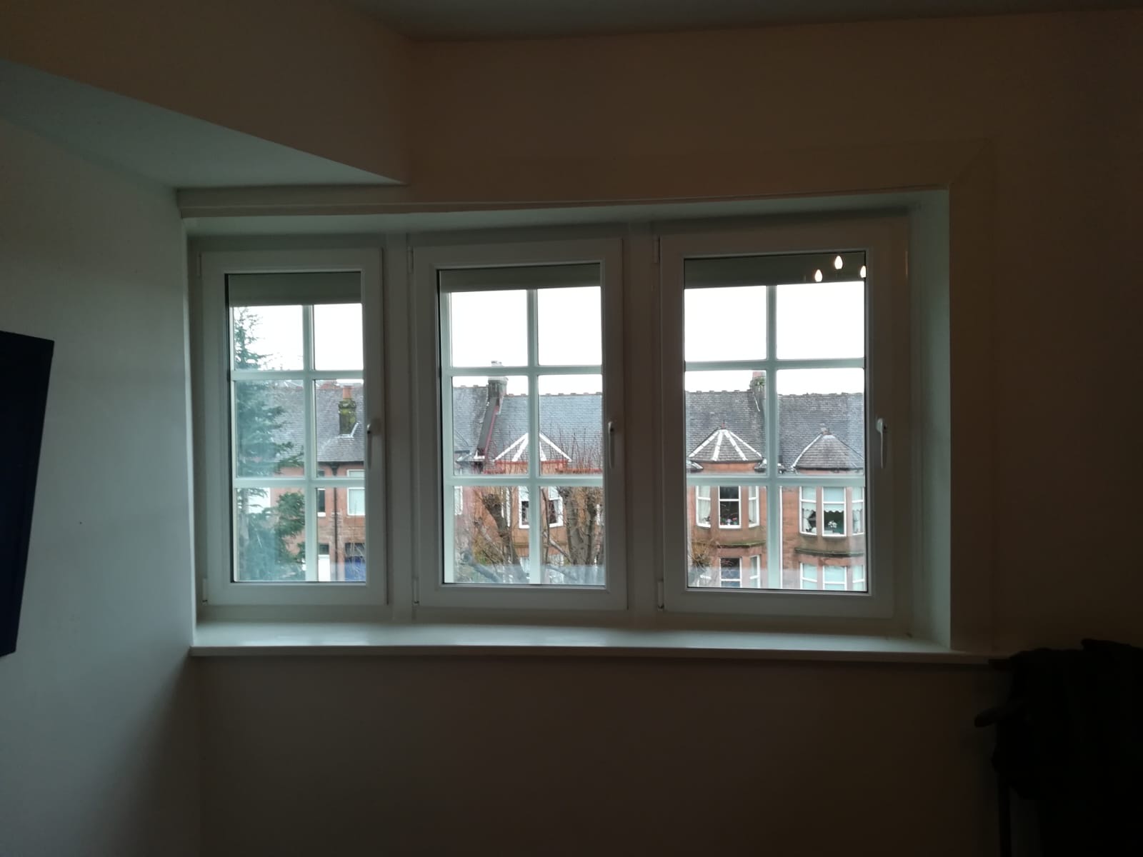 Triple white uPVC casement windows with Georgian bars overlooking Glasgow tenements
